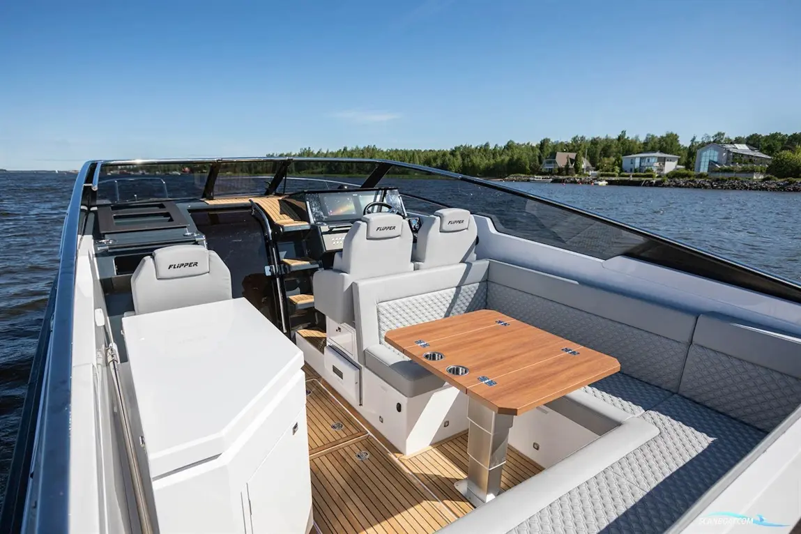 Stylish motorboat interior featuring dual grey captain seats, a wooden table, and tech dashboard over a scenic water view.